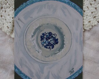 May include: A white ceramic plate with a blue floral design in the center. The plate has a blue and white trim around the edge.