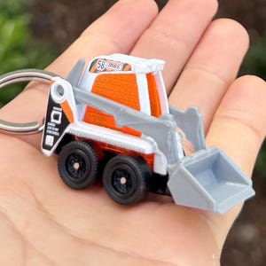 May include: A white ceramic mug with a black handle and the text "But First, Coffee" in a handwritten style. The mug is on a white surface. The mug is approximately 10 cm tall.