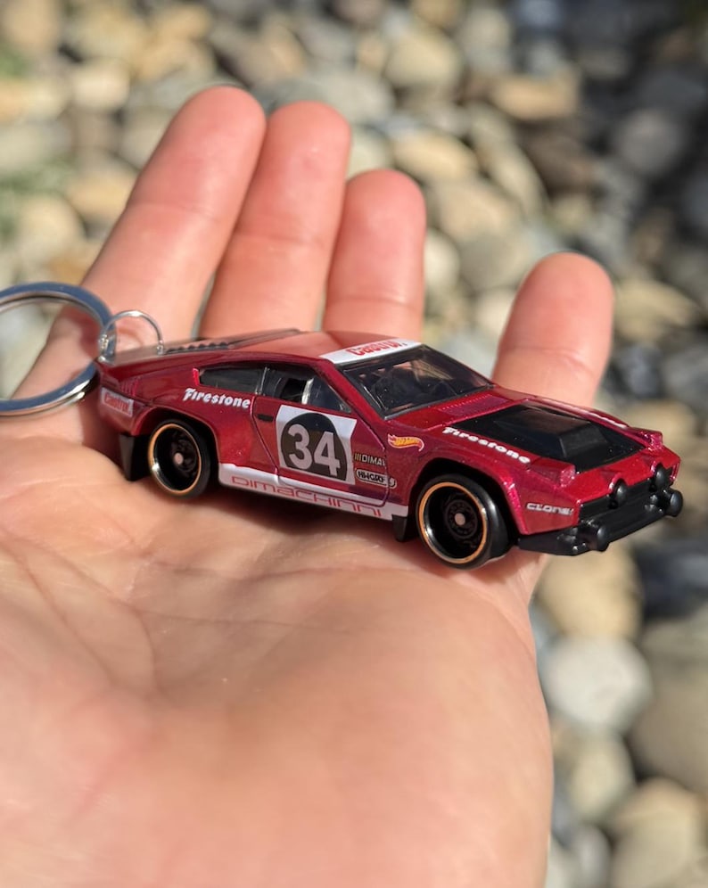 May include: A white ceramic mug with a black handle and the text "But First, Coffee" in a bold, black font. The mug is set against a blurred background, suggesting a cozy setting.