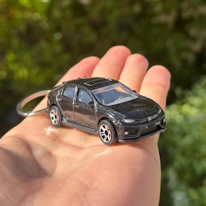 May include: A black die-cast model car keychain. The miniature car has a detailed design with silver wheels and a sunroof. The keychain ring is silver. The car is approximately 2 inches long.
