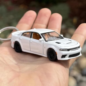 以下が含まれることがあります： 黒い車輪とシルバーのキーホルダーが付いた白いダイキャストモデルカー。 ミニチュア車には、フロントグリル、ヘッドライト、インテリアなどの詳細な機能があります。 車の長さは約10cmです。