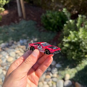 May include: A white ceramic mug with a colorful floral design. The mug features a handle and a wide rim. The flowers are in shades of pink, purple, and yellow. The mug is likely for beverages.