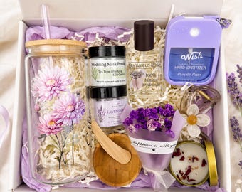 Könnte beinhalten: Eine Geschenkbox mit einem Glastrinkbecher mit rosa Chrysanthemen-Aufdruck, Teebaum-Maskenpulver, Damaszener-Rosenwasser-Spray, einem violetten Wish-Handdesinfektionsmittel, Lavendel-Badezusatz, einem Holzspatel, getrockneten violetten Blumen und einer Kerze.