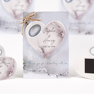 May include: White ceramic heart-shaped bottle opener with a rustic design and the text "Sophia & Henry July 14, 2024".