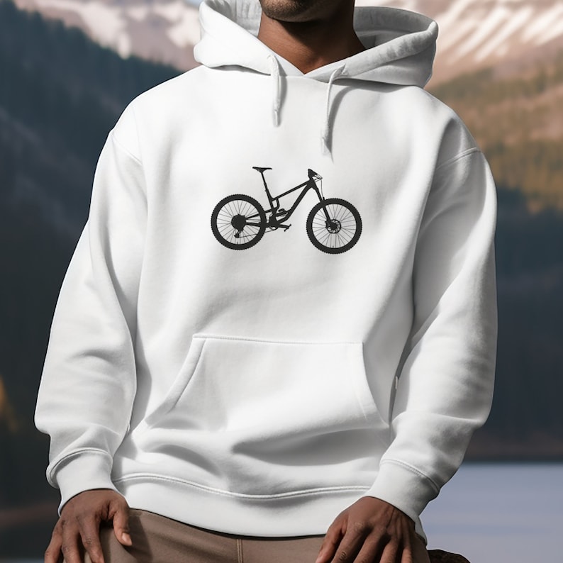 man wearing white hoodie in foreground with downhill mountain bike graphic, mountains in background