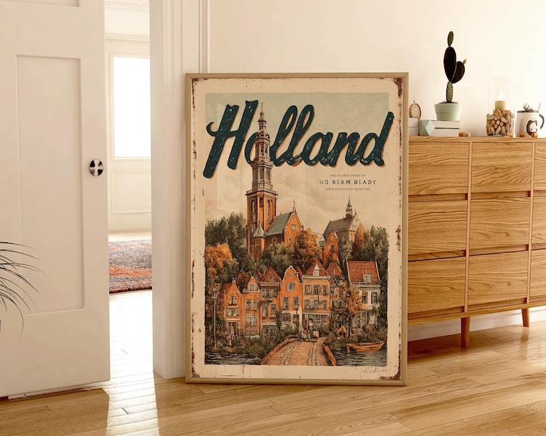May include: A framed vintage-style poster with the word "Holland" in teal script. The artwork depicts a quaint European town with a church steeple, colorful buildings, and a bridge. The poster has a distressed, aged appearance.