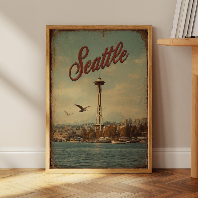 May include: A vintage-style framed print featuring the Seattle skyline, with the Space Needle prominently displayed. The word "Seattle" is written in a red script font above the Space Needle. Two birds fly in the sky above the city and water.