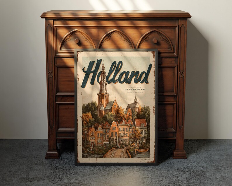 May include: A vintage-style Holland travel poster with a detailed illustration of a European town, featuring a church steeple and colorful buildings. The poster is framed and leans against a dark wooden cabinet.