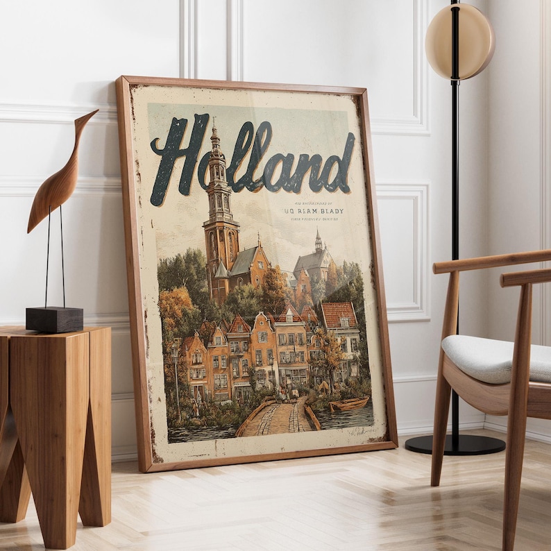 May include: A framed vintage-style print featuring the word "Holland" in large, dark blue lettering. The artwork depicts a quaint European town with a church, houses, and a bridge. The print has a distressed, aged appearance.