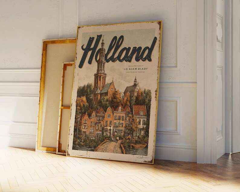 May include: A vintage-style poster with the word "Holland" in a dark blue script. The poster depicts a detailed illustration of a European town with a church, buildings, and a bridge. The poster is leaning against a white wall and a framed canvas.