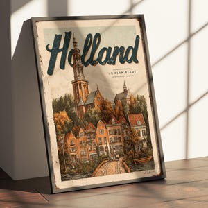 May include: Framed vintage-style print of Holland, featuring a detailed illustration of a Dutch town with a church steeple, colorful houses, and a bridge over a canal. The word "Holland" is in large, stylized letters.