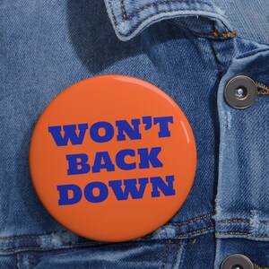 May include: Orange button with the text "WON'T BACK DOWN" in blue letters.