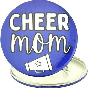 May include: Blue and white button with the text "cheer mom" and a white megaphone graphic.