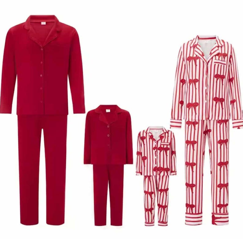 May include: Three sets of matching pajamas. Two sets are solid red, and one set is white with red stripes and red bow accents. Each set includes a button-down top and pants. The pajamas are displayed on a white background.