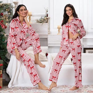 May include: Red and white striped pajama set with red bow accents. The set includes a button-down top with a notched collar and long sleeves, and matching pants. The pajamas are made of a soft, silky material.