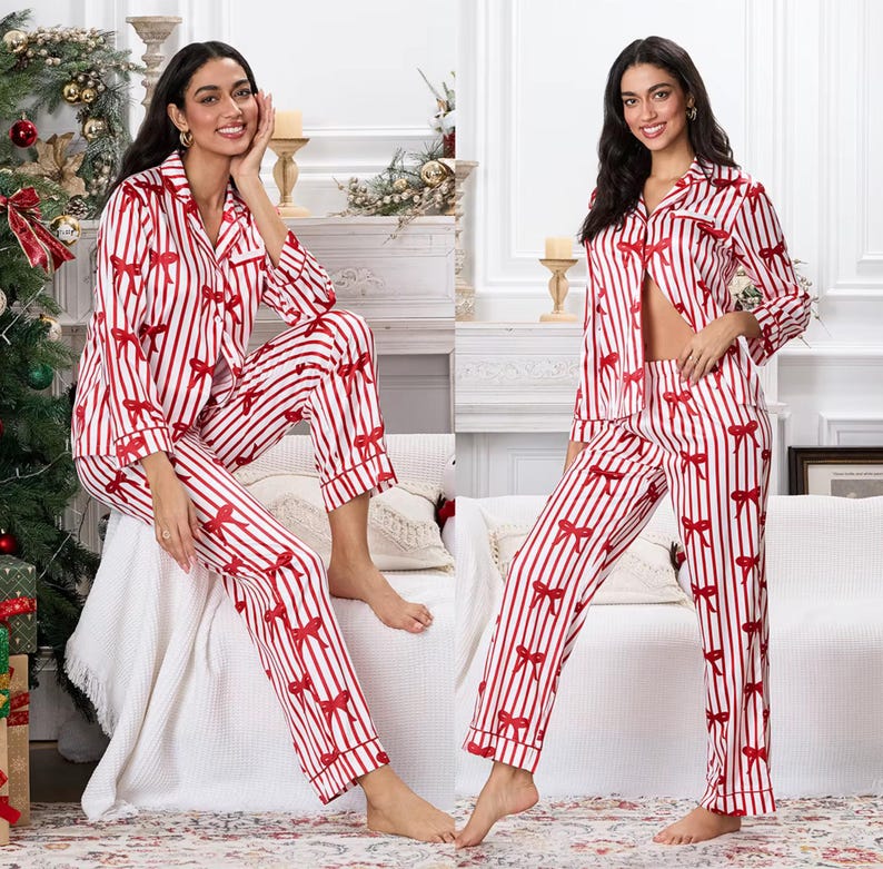 May include: Red and white striped pajama set with red bow accents. The set includes a button-down top with a notched collar and long sleeves, and matching pants. The pajamas are made of a soft, silky material.