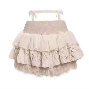 May include: A beige ruffled skirt with lace trim. The skirt has a gathered waistband and multiple layers of ruffles.