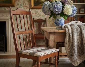 May include: A wooden chair with a spindle back and a seat upholstered in a brown, white, and grey plaid fabric. The chair features a warm brown finish and is positioned next to a wooden table holding a blue and white ceramic pitcher of hydrangeas.
