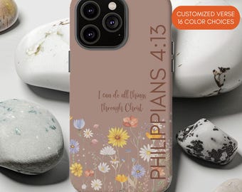 Puede incluir: Una funda de teléfono malva con un estampado floral de flores silvestres amarillas, blancas y azules en la parte inferior. El texto "I can do all things through Christ" y "PHILIPPIANS 4:13" está impreso. Una etiqueta naranja dice "CUSTOMIZED VERSE 16 COLOR CHOICES".