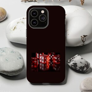 May include: A dark burgundy phone case featuring a cluster of red dice with white dots. The dice are arranged on a black surface, creating a gambling or game-themed design. The case has a camera module with three lenses.