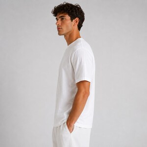 May include: A plain white short-sleeved t-shirt with a crew neckline. The garment is constructed from a solid white fabric and features a standard fit with short sleeves that reach the mid-bicep area, providing a clean and simple appearance.