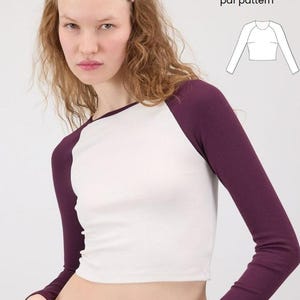 Puede incluir: Un top corto blanco con mangas raglán y mangas largas de color púrpura oscuro. El top se combina con unos vaqueros azules. El texto de la imagen dice "Raglan Sleeve Crop Top" y "pdf pattern".