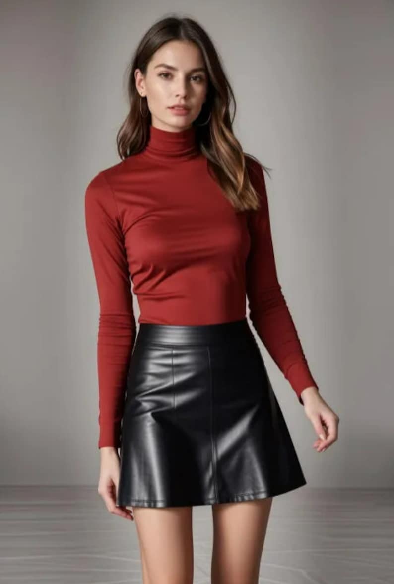 May include: A woman wearing a red turtleneck sweater and a black leather skirt.