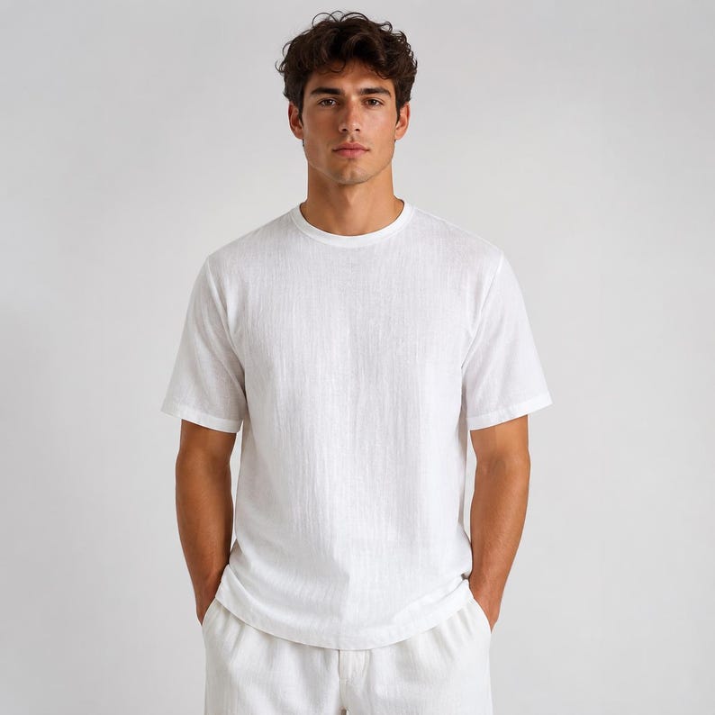 May include: A short-sleeved, crew-neck t-shirt in a solid white color. The fabric features a subtle, vertical textured weave throughout the garment. The shirt has a standard fit with a straight hemline and simple, clean lines across the chest and sleeves.