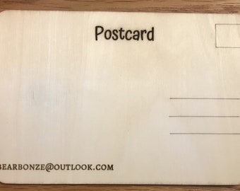 May include: A blank wooden postcard with the word "Postcard" printed at the top and a space for a stamp in the upper right corner. The bottom of the postcard has the email address "bearbonze@outlook.com" printed on it.