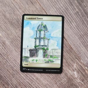 May include: A custom-painted card featuring a watercolor illustration of a tower with the text "Command Tower" and "Land". The tower is depicted in a detailed, artistic style with a blue sky background. The card is labeled "NOT FOR TOURNAMENT PLAY".