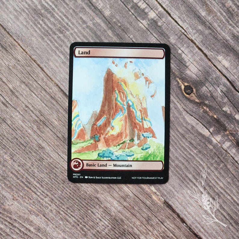 May include: A Magic: The Gathering proxy card featuring a watercolor illustration of a mountain landscape. The card has a black border and text that reads "Land" at the top and "Basic Land - Mountain" at the bottom. The artwork depicts a brown mountain with blue and green accents.