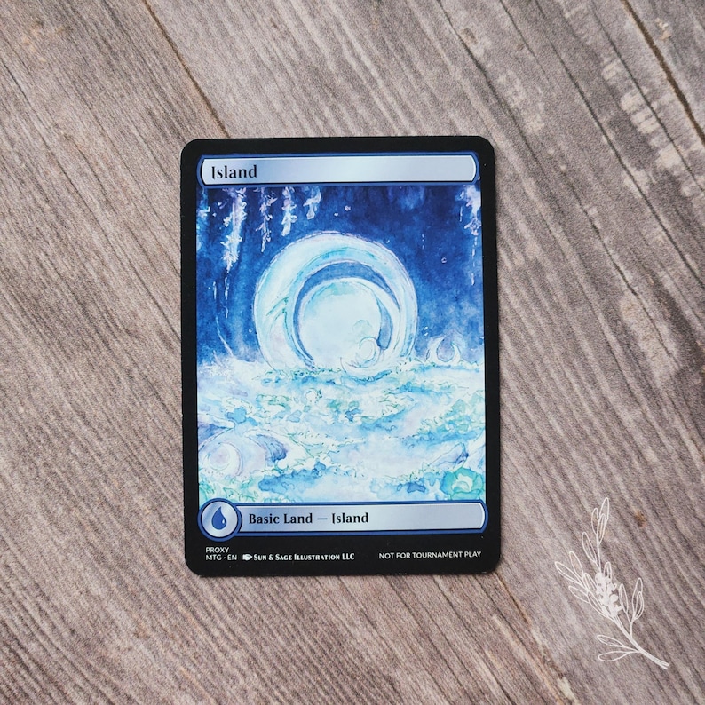 May include: A Magic: The Gathering card featuring an "Island" scene with a blue and white watercolor design. The card has a black border and includes the text "Basic Land - Island" and "Not for Tournament Play."