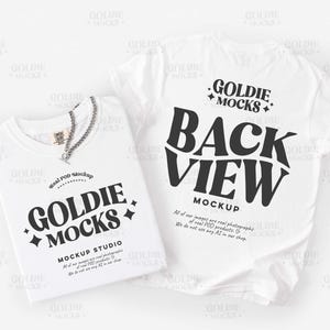 Op de afbeelding: Twee witte t-shirts met de tekst "GOLDIE MOCKS" en "BACK VIEW MOCKUP" in het zwart. Eén shirt heeft een zilveren ketting. De afbeelding is een mockup voor een kledingmerk.