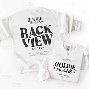 Könnte beinhalten: Zwei weiße Sweatshirts werden gezeigt. Das größere hat die Worte "BACK VIEW MOCKUP" in großen schwarzen Buchstaben. Das kleinere Sweatshirt hat die Worte "GOLDIE MOCKS" in Schwarz. Die Sweatshirts befinden sich auf weißem Hintergrund.