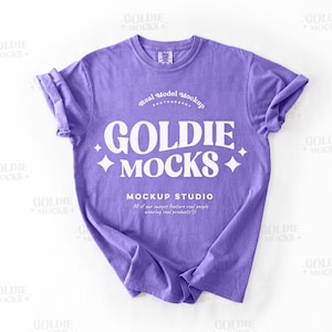 May include: A purple t-shirt with a white graphic that says "Goldie Mocks" and "Mockup Studio".