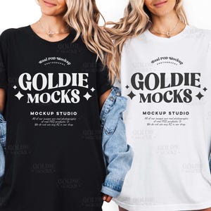 May include: Two t-shirts, one black and one white, each with the text "GOLDIE MOCKS" in a bold, stylized font. The text is accompanied by decorative starbursts. Below the text is "MOCKUP STUDIO" and additional text.