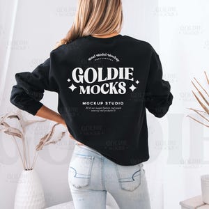 Puede incluir: Una sudadera negra de manga larga con un estampado gráfico blanco que dice "Goldie Mocks Mockup Studio".