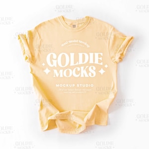 Könnte beinhalten: Ein gelbes T-Shirt-Mockup mit dem Text "Goldie Mocks" und "Mockup Studio" auf der Vorderseite.