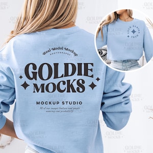 May include: A light blue sweatshirt with a black graphic that says "GOLDIE +MOCKS+" and "MOCKUP STUDIO" with the text "All of our images feature real people wearing real products".