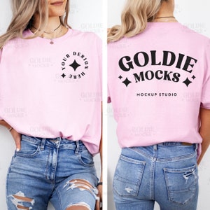Puede incluir: Una camiseta rosa con un diseño gráfico negro en la parte delantera y trasera. El diseño delantero dice "Your Design Here" con una estrella negra. El diseño trasero dice "Goldie Mocks" con una estrella negra a cada lado. El texto "Mockup Studio" está debajo del diseño.