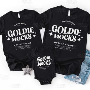 Può includere: Un set coordinato di magliette nere e un body per neonati. Le magliette e il body presentano la scritta bianca "GOLDIE MOCKS". Le magliette sono a maniche corte e il body è un body a maniche corte. Nell'immagine è presente anche un paio di jeans.