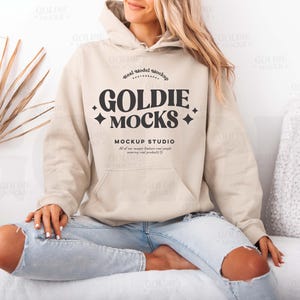 Könnte beinhalten: Ein beiger Hoodie mit dem Text "Real Model Mockup Goldie Mocks Mockup Studio All of our images feature real people wearing real products" auf der Vorderseite.