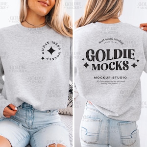 May include: A gray sweatshirt mockup with a black graphic on the back that says "Goldie Mocks" and "Mockup Studio" with a small heart. The front of the sweatshirt has a black circle with the text "Gildan 18500 Mockup" and a diamond shape.