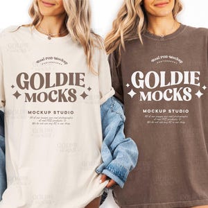 Puede incluir: Dos camisetas, una crema y otra marrón, con el texto "GOLDIE MOCKS" en una fuente estilizada. Las camisetas se muestran en una persona. También es visible el texto "MOCKUP STUDIO".