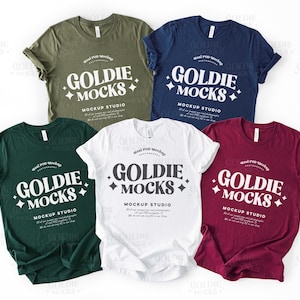 May include: Five t-shirts in different colors, including green, white, navy blue, and burgundy. Each shirt has the text "Goldie Mocks" printed on the front in a white, retro-style font with a star design.
