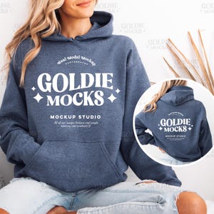 May include: A navy blue hoodie with a white pocket and a white logo that says "Goldie Mocks" and "Mockup Studio". The logo is in a retro font style. The hoodie is being worn by a person.