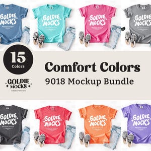 May include: A mockup bundle featuring t-shirts in various colors, including blue, teal, pink, and gray, paired with denim shorts and sneakers. The text "Comfort Colors 9018 Mockup Bundle" is displayed, along with the "Goldie Mocks" logo and "15 Colors".