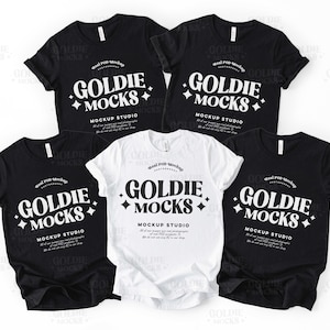 Könnte beinhalten: Fünf T-Shirts, vier schwarze und ein weißes, flach auf einer weißen Oberfläche liegend. Jedes Shirt hat den Text "Goldie Mocks" und "Mockup Studio" in weißer, retro-artiger Schrift auf der Vorderseite.