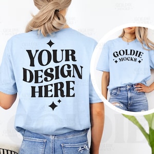 May include: Light blue t-shirt with the text "YOUR DESIGN HERE" in large black letters on the back. The front of the shirt has the text "GOLDIE MOCKS" in black. The shirt is a mock-up for custom designs.