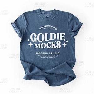 May include: A blue t-shirt with a white graphic that says "GOLDIE MOCKS" and "MOCKUP STUDIO" with a star design. The text says "Real Model Mockup Photography".